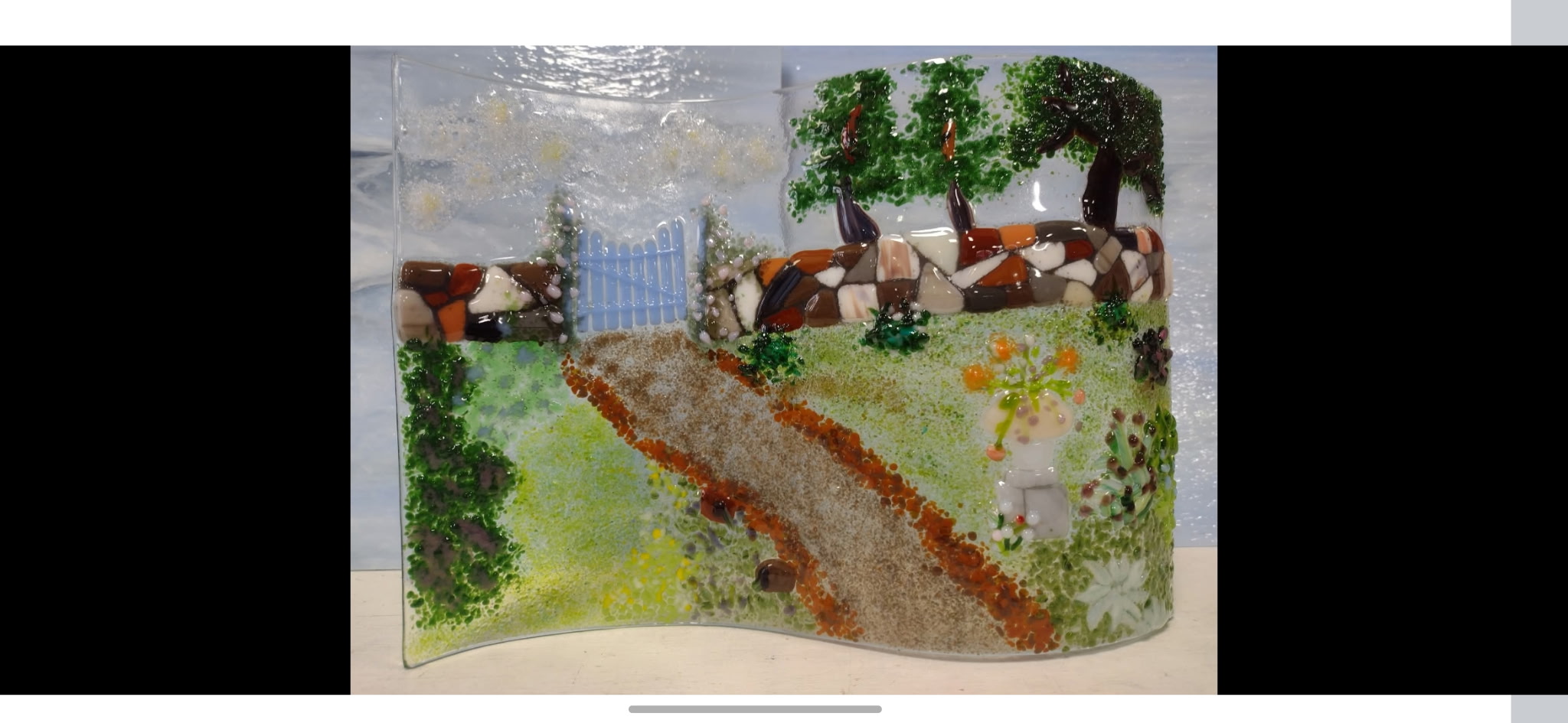 Fused glass wall panel with stone-lined garden path leading to a gate